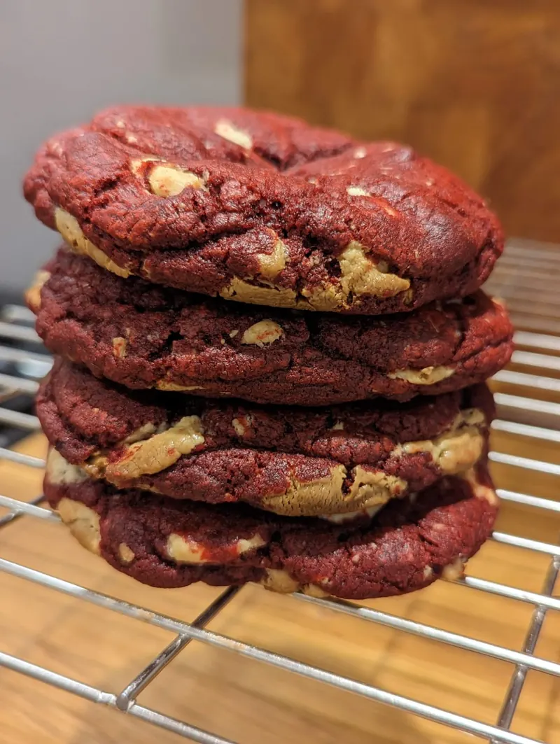 A tall stack of thick red velvet cookies studded with white chocolate chunks