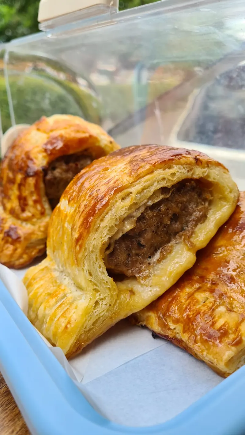 Golden, flaky sausage rolls, one cut open to show the filling